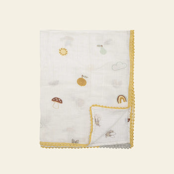 The Bloomingville Agnes Blanket by Bloomingville is a white muslin baby blanket featuring yellow scalloped edges and playful pastel patterns of mushrooms, bees, rainbows, clouds, suns, and fruit.