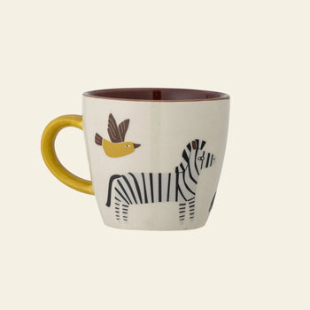 The Bloomingville Belina Cup by Bloomingville is a stoneware mug with a yellow handle, featuring zebra and flying yellow bird motifs on a cream background, and has a brown interior.