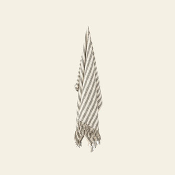 The Bloomingville Binnur Throw from Bloomingville, featuring beige and white stripes and fringed edges, is crafted from woven cotton and displayed against a light background.