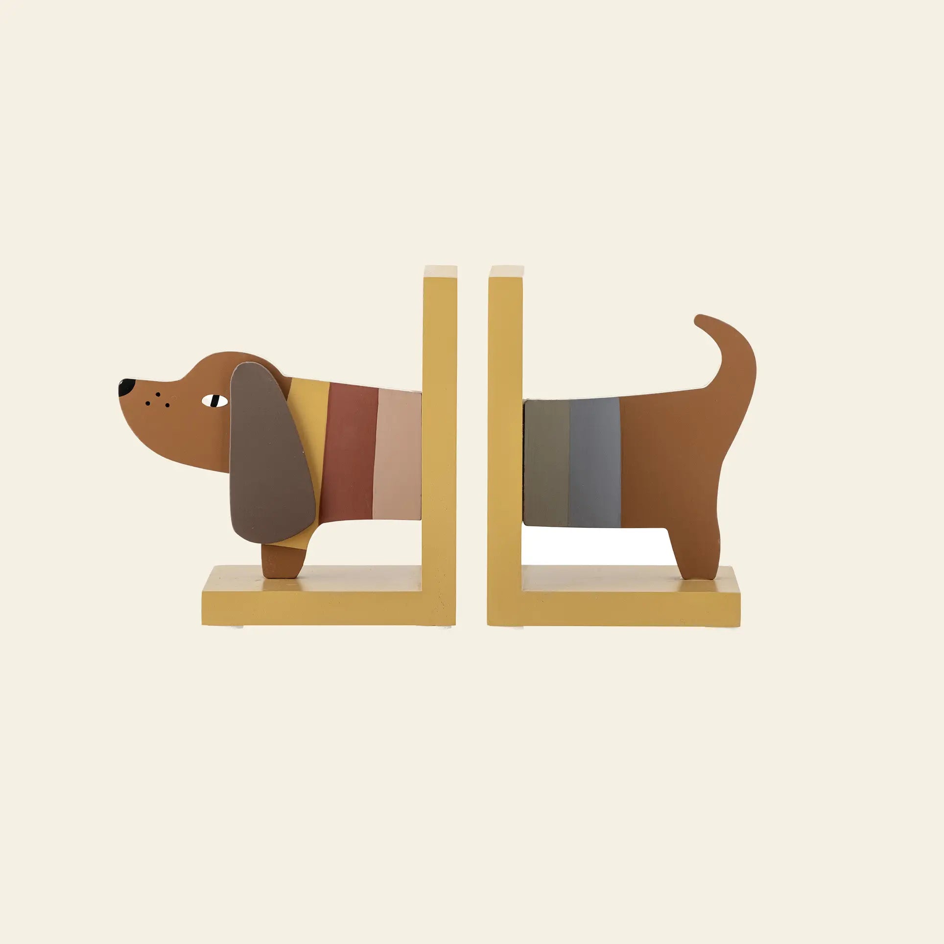 Two yellow Bloomingville Charlie Bookend pieces form a cartoon dog with brown ears and stripes. Made from FSC-certified wood, these playful Bloomingville accessories add color and fun to any childrens room. The background is plain beige.