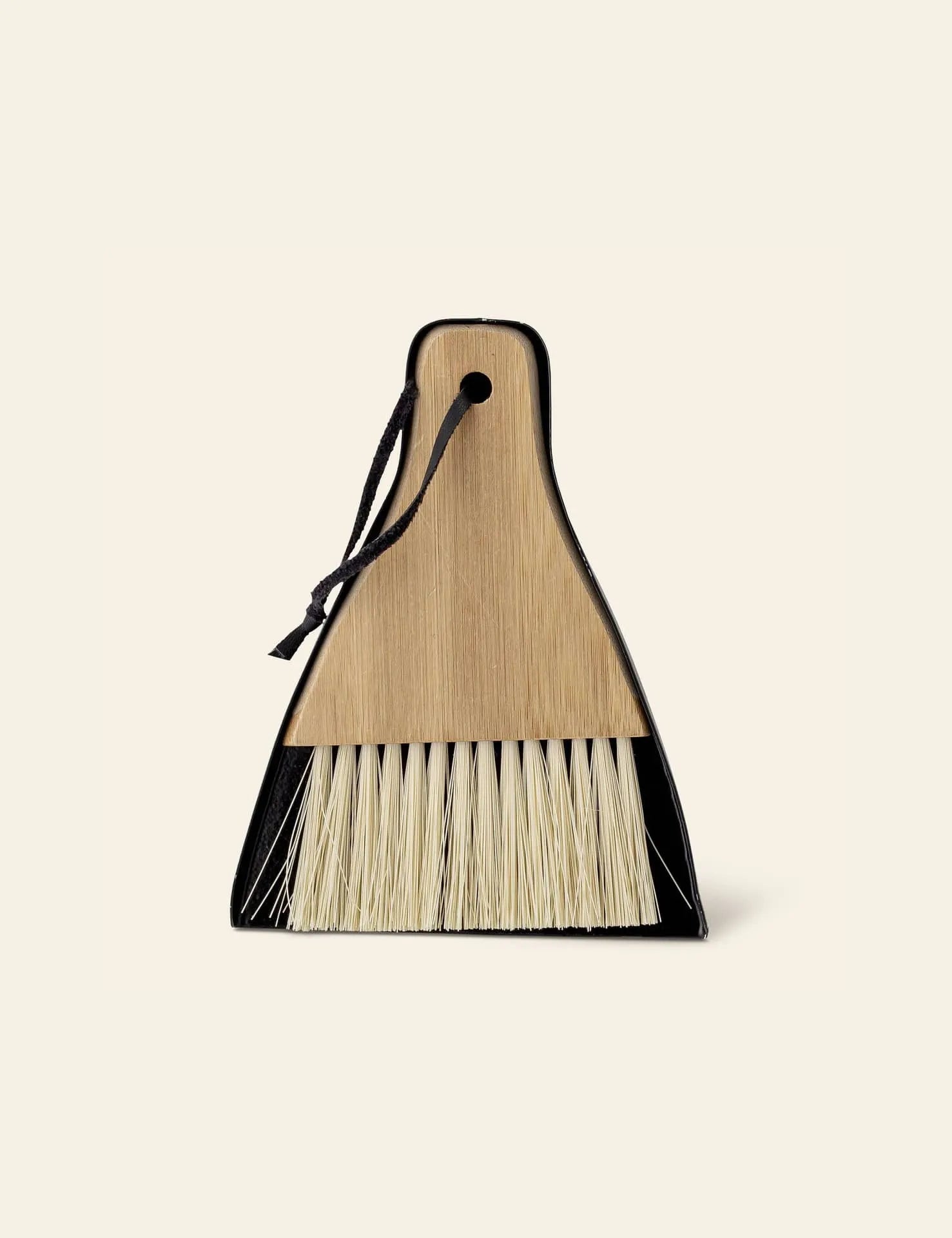 The Bloomingville Cleaning Dustpan & Broom, featuring natural bristles and a wooden handle secured with a black string, offers minimalist design—ideal for modern homes. From the Bloomingville brand.