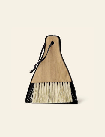 The Bloomingville Cleaning Dustpan & Broom, featuring natural bristles and a wooden handle secured with a black string, offers minimalist design—ideal for modern homes. From the Bloomingville brand.