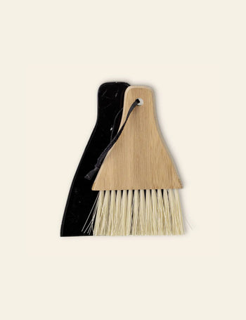 The Bloomingville Cleaning Dustpan & Broom features a slim black dustpan and a minimalist light wood brush with white bristles and a storage loop—perfect for stylish, compact cleaning.