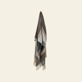 The Bloomingville Isnel Throw, made from recycled cotton, features stripes and chevron patterns in brown, black, cream, and taupe. Finished with tassels, this fringed blanket by Bloomingville adds texture and warmth to any light beige wall.