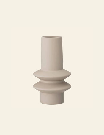 The Bloomingville Isold Vase by Bloomingville is a modern matte beige stoneware piece with a cylindrical shape and two wide, disc-like central ridges, adding natural charm against a light cream backdrop.