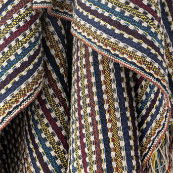 The Bloomingville Lazzario Throw by Bloomingville features a close-up of woven recycled cotton, showcasing geometric stripes in blue, yellow, red, and white with textured raised threads for a cozy, artful layer.