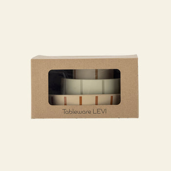 A cardboard box with a clear window displays the Bloomingville Levi Tableware Set—stacked ceramic pieces with a simple striped design—labeled “Bloomingville” on the front; a charming gift for young children.