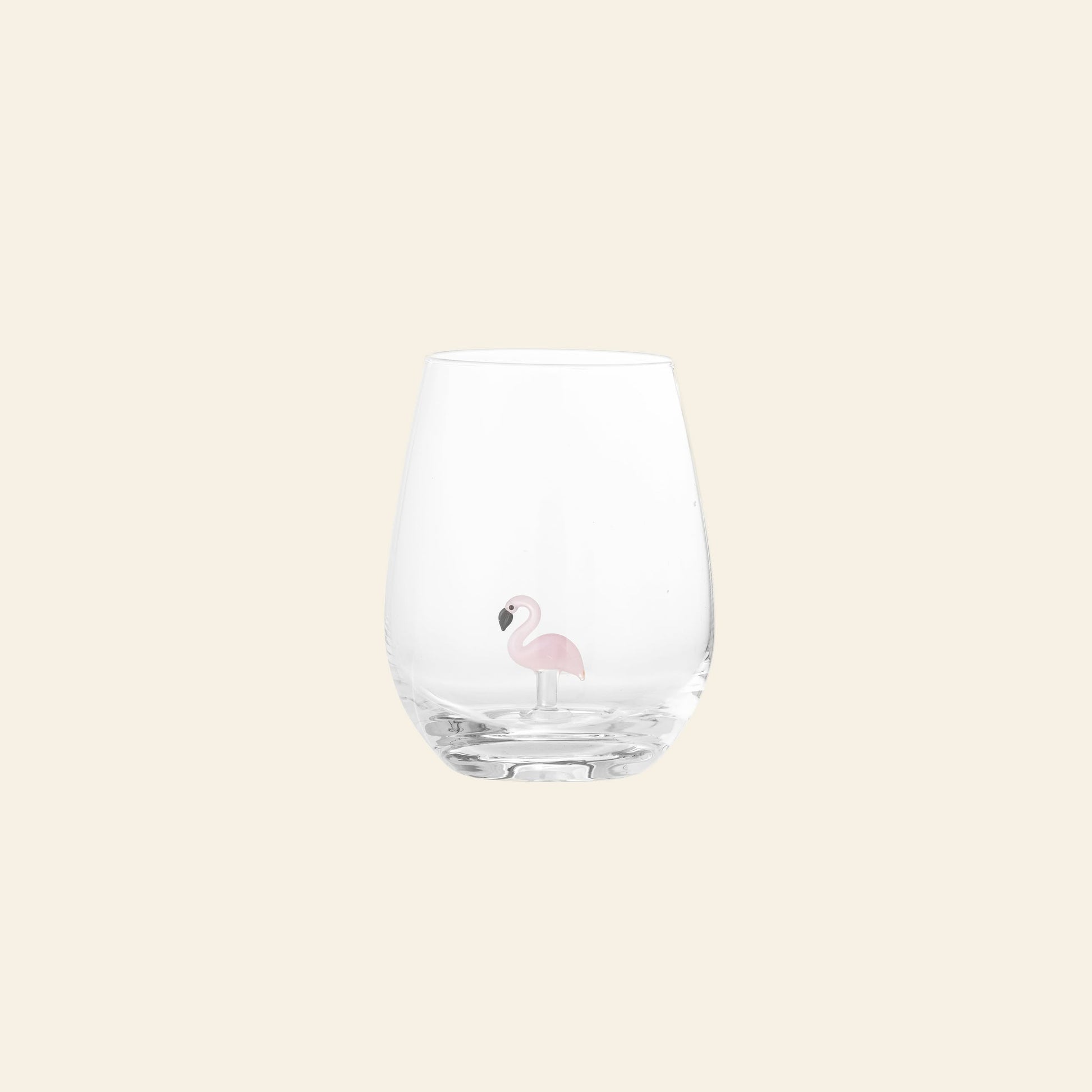 The Bloomingville Misa Drinking Glass by Bloomingville is a clear, handcrafted glass featuring a small pink flamingo illustration, displayed on a plain, light beige background.