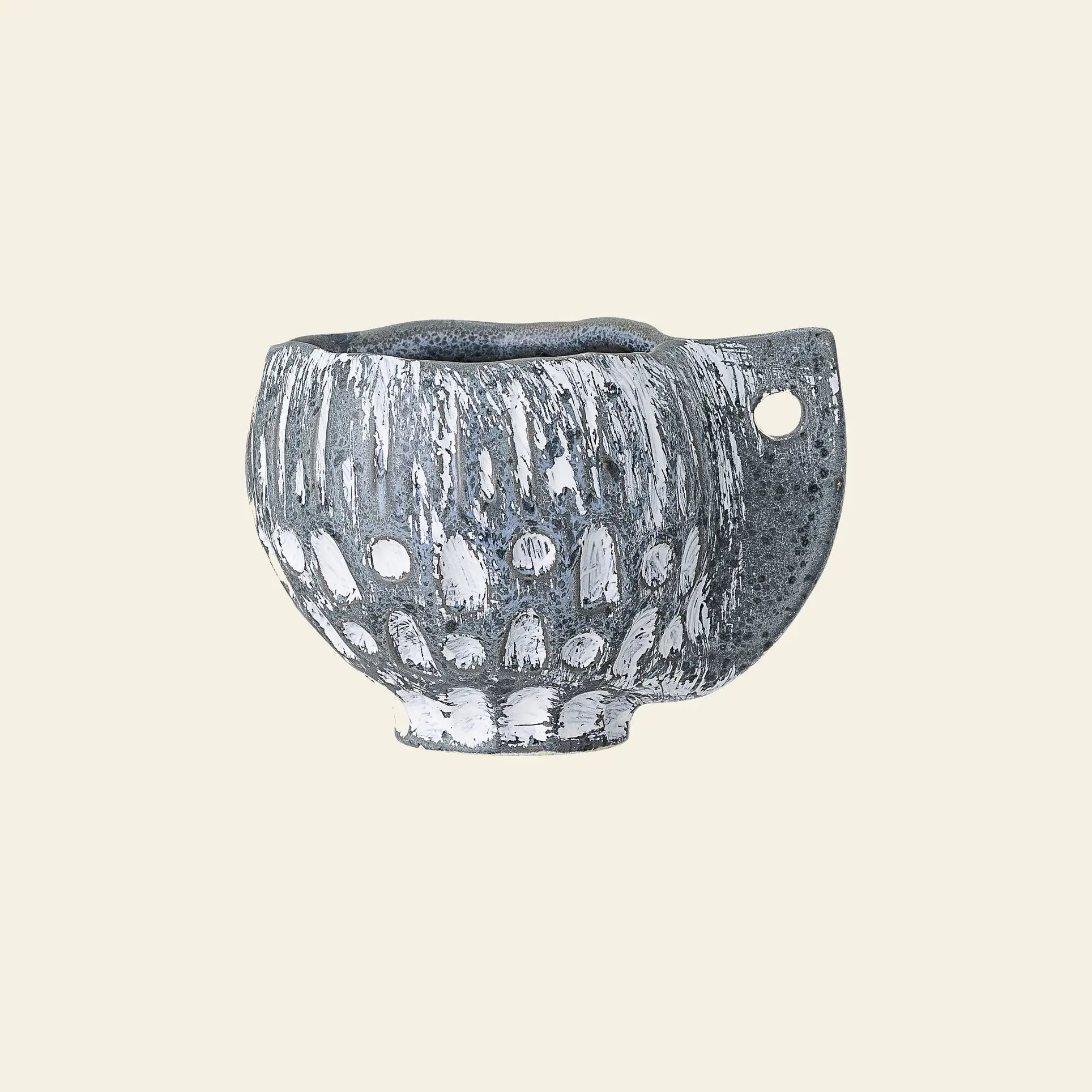 The Bloomingville Oney Flowerpot by Bloomingville is a small, handmade ceramic piece with a rough gray and white finish, rounded body, and flat handle with a circular hole—ideal as a decorative flowerpot cover against any plain beige background.