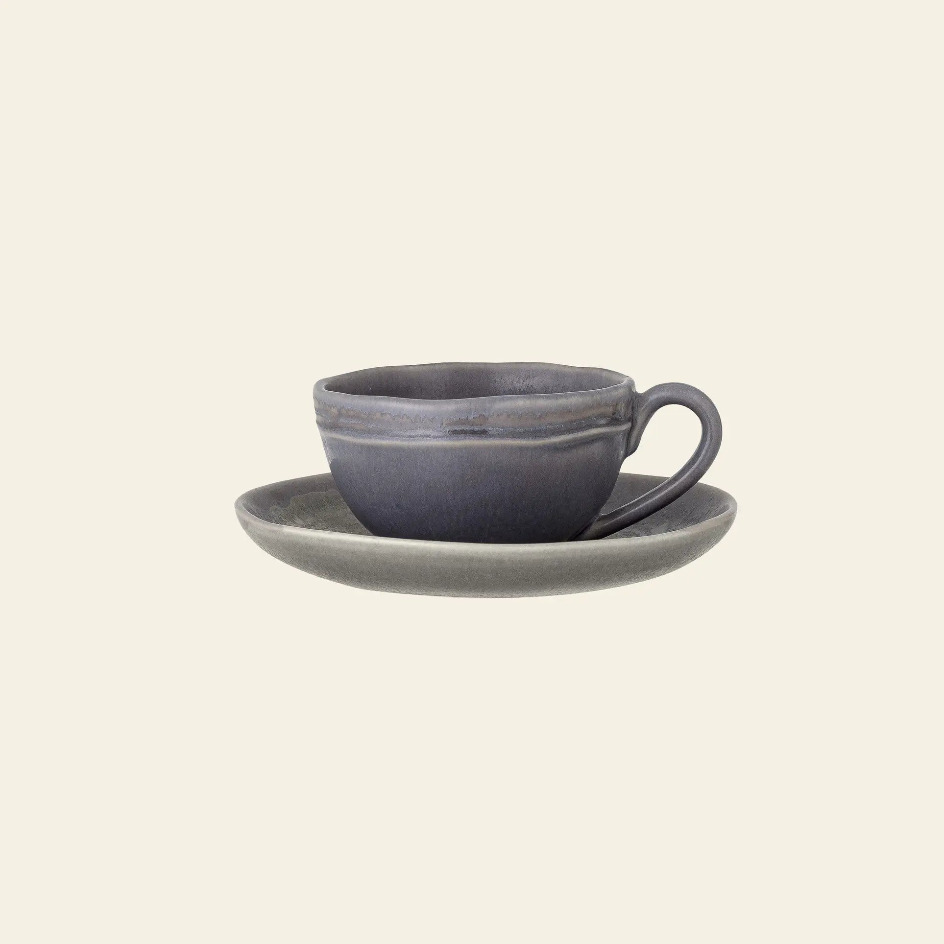 The Bloomingville Raben Cappuccino Cup With Saucer by Bloomingville, in elegant dark gray stoneware with a handle, is displayed on a matching saucer against a plain cream background.