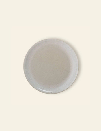 The Bloomingville Taupe Plate by Bloomingville is a round stoneware plate in light beige with subtle speckled patterns, shown from above on a matching light background.