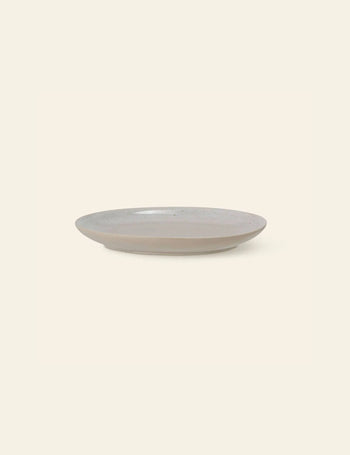 The Bloomingville Taupe Plate is a simple, round stoneware piece with a slightly raised rim, featured in light taupe against an off-white background.