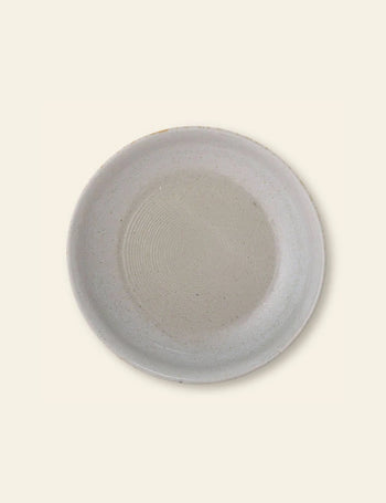 The Bloomingville Taupe Serving Bowl by Bloomingville features a simple round design with a light gray finish and subtle speckles, making it a stylish addition to any kitchen collection. Shown on a plain off-white background.
