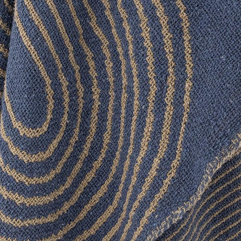 Close-up of blue cotton fabric with wavy, parallel tan stripes forming a graphic, textured pattern inspired by the Bloomingville Tiffanie Throw.