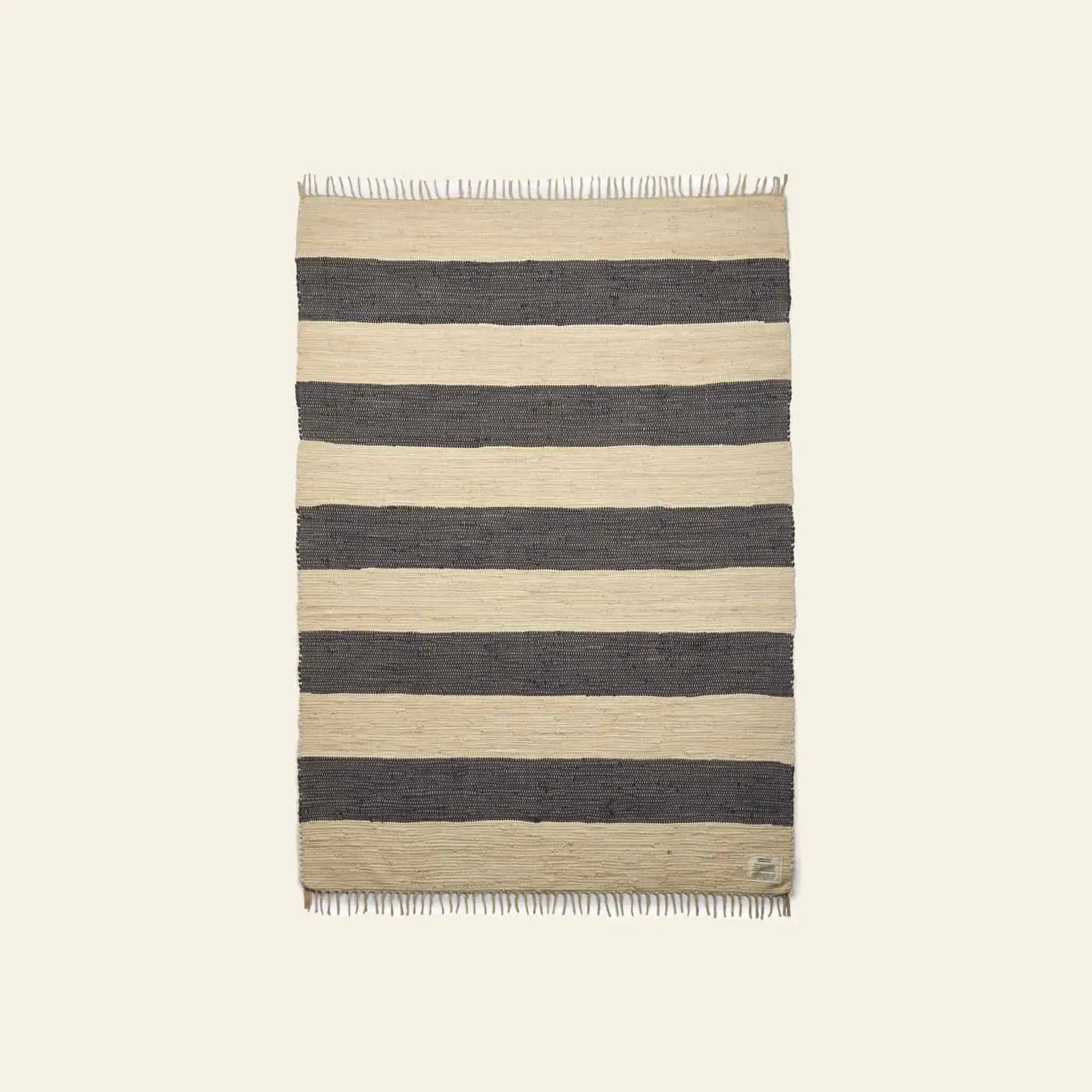 The Bongusta Chindi Rug (140x200) by Bongusta is a rectangular handcrafted rug from India with wide beige and dark gray horizontal stripes, short fringe on both ends, shown on a light background.