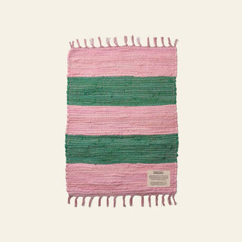The Bongusta Chindi Rug (45x60) by Bongusta is handcrafted in India from surplus cotton, with horizontal pink and green stripes, fringe on both ends, and a rectangular corner label, shown on a plain light background.