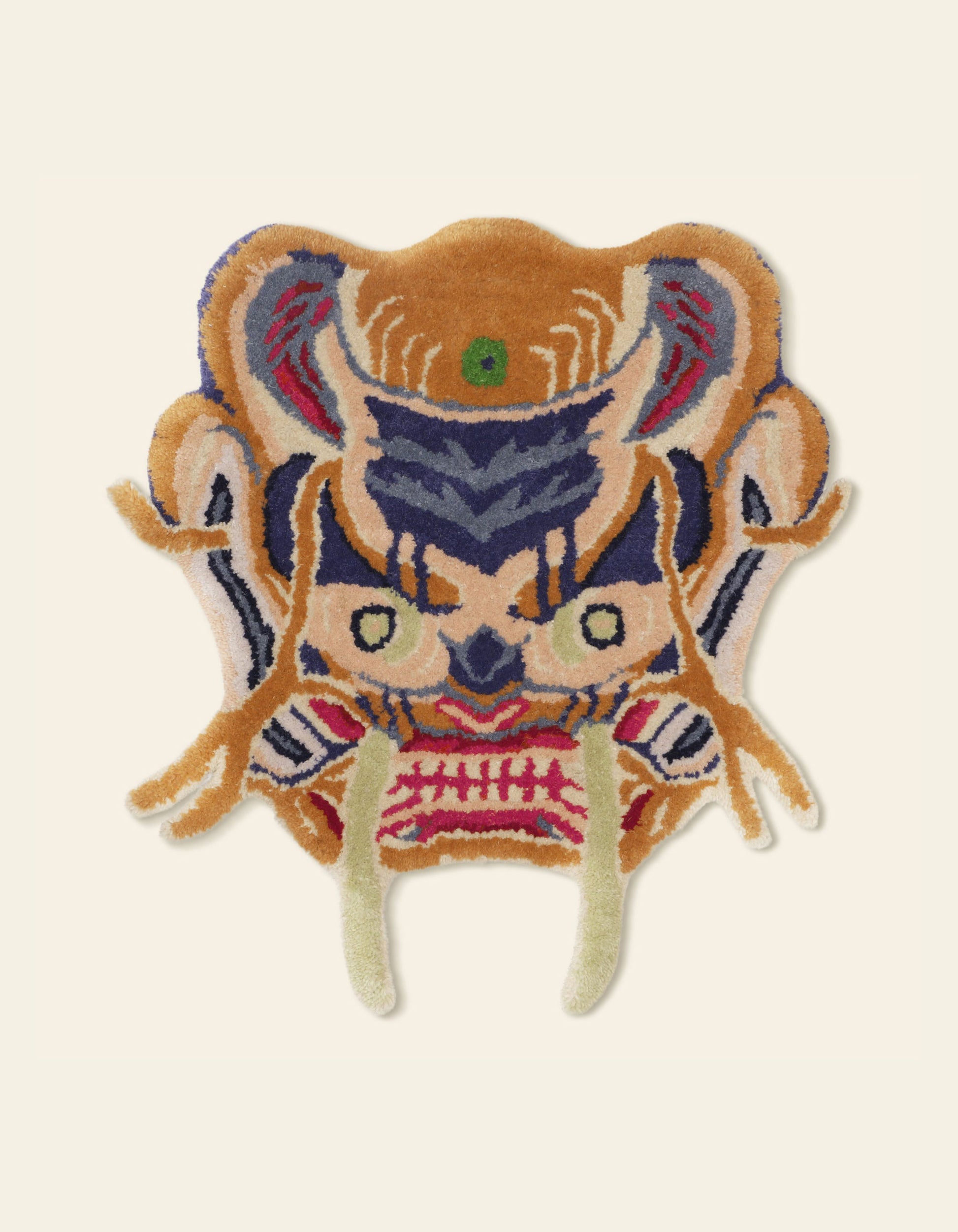 The Bongusta Dragon Face Rug by Bongusta is a colorful, intricately designed wool rug shaped like a stylized animal face, with large fangs, pointed ears, and bold orange, blue, cream, green, and pink patterns on a pale background.