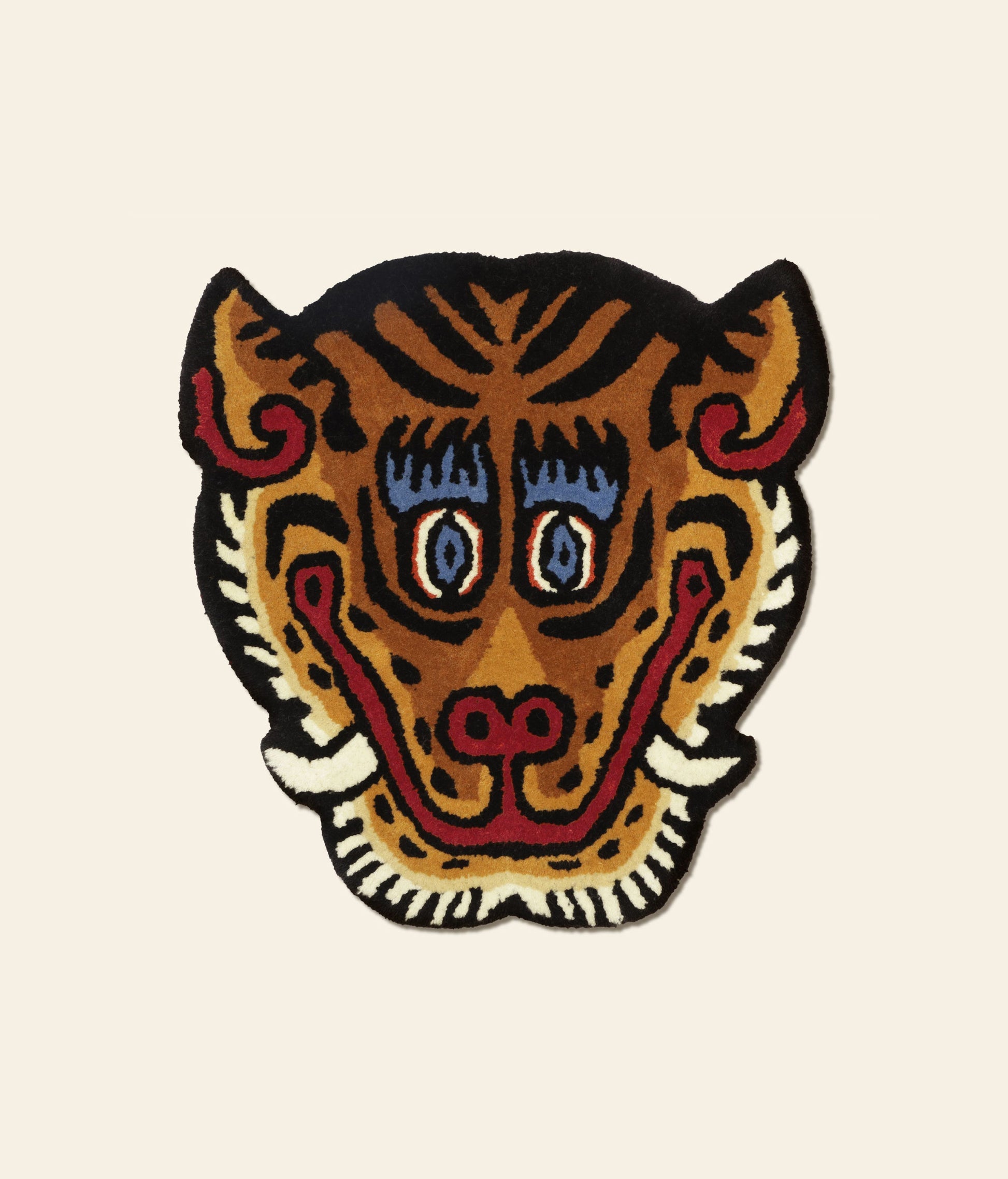 The Bongusta Tiger Face Rug by Bongusta is a colorful, cartoon-style handwoven rug shaped like a tiger’s head, with bold black, orange, red, blue, and white details plus large eyes and expressive features on a light background.