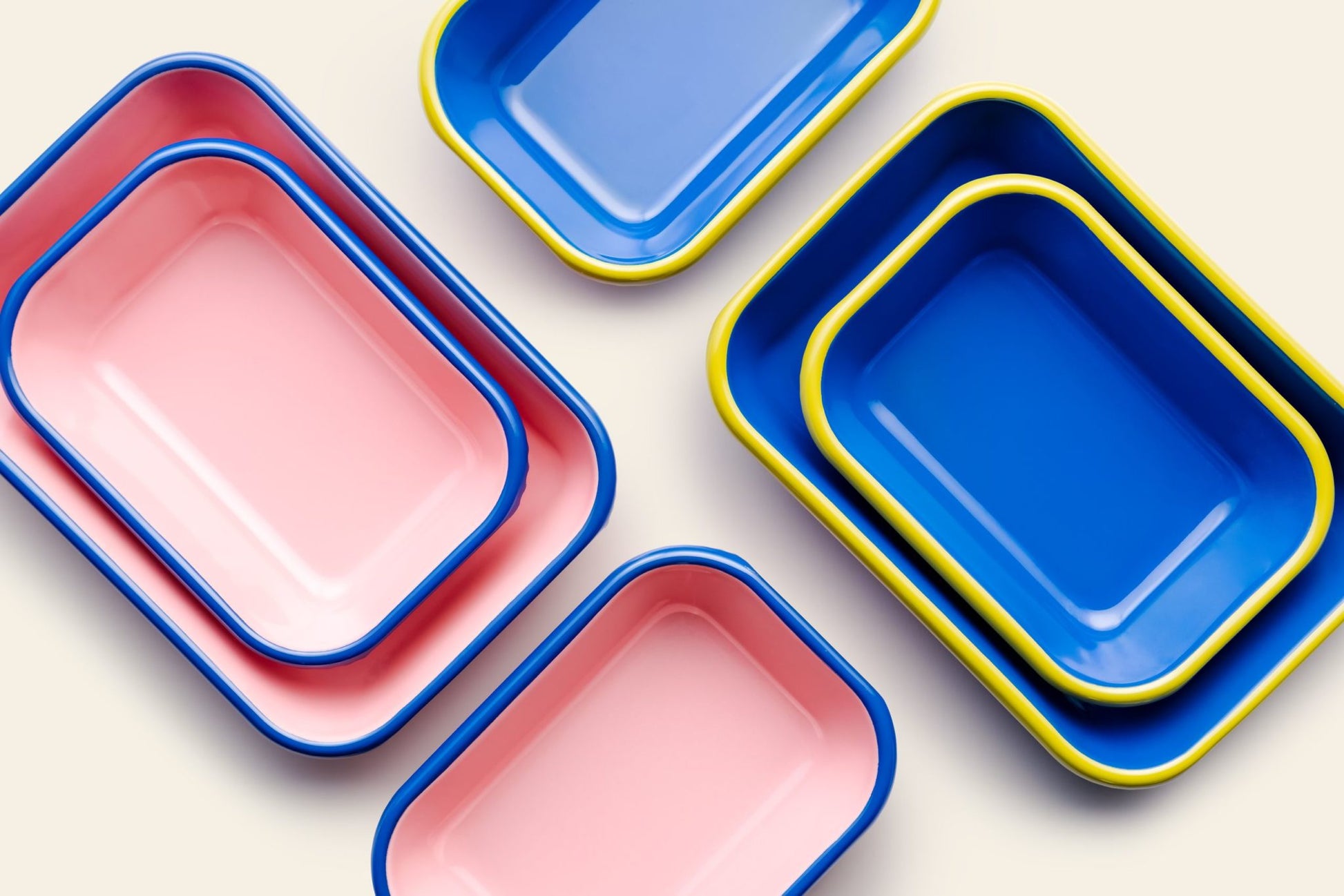 The Bornn Enamelware Colorama Baking Dish, Medium, by Bornn Enamelware, features a handmade design with vibrant blue and pink hues, yellow and blue rims, and geometric patterns for a striking color-coordinated display.