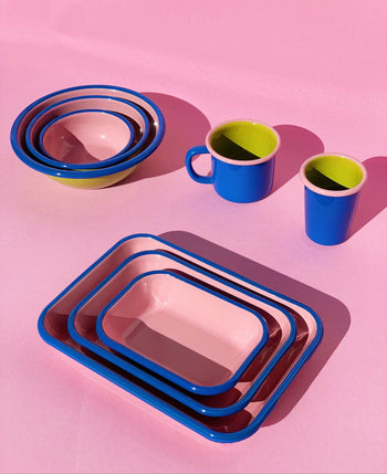 A set of colorful Bornn Enamelware Colorama Baking Dishes (Medium) by Bornn Enamelware sits on a pink surface, featuring vibrant handmade design and adding a playful touch to your table setting.