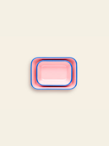 Two rectangular pink Bornn Enamelware Colorama Baking Dishes with blue rims, one nested in the other, display their vibrant handmade style on a light beige background.