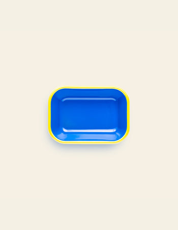 The Bornn Enamelware Colorama Baking Dish, Small, by Bornn Enamelware, is a rectangular blue tray with rounded corners and a yellow rim, handmade and shown on a light beige background.