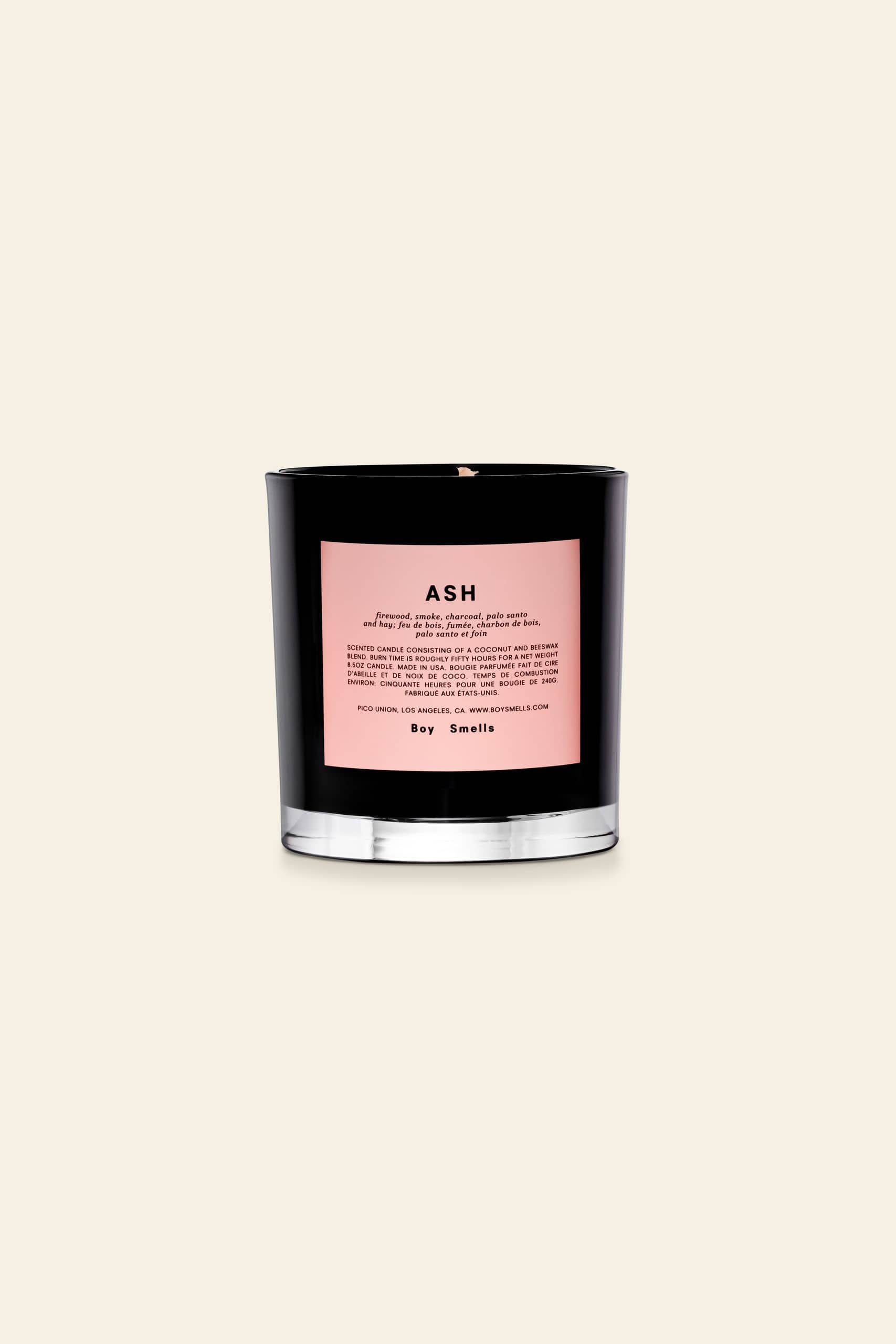 The Boy Smells Ash Scented Candle 8.5oz features a black glass vessel with a pink label, offering notes of lemon peel and dry hay—a perfect addition to any nature lovers candle collection.