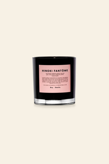 The Boy Smells Hinoki Fantôme Scented Candle 8.5oz features a black glass jar with a pale pink label, capturing Japanese cypress notes, and is showcased against a plain beige background.
