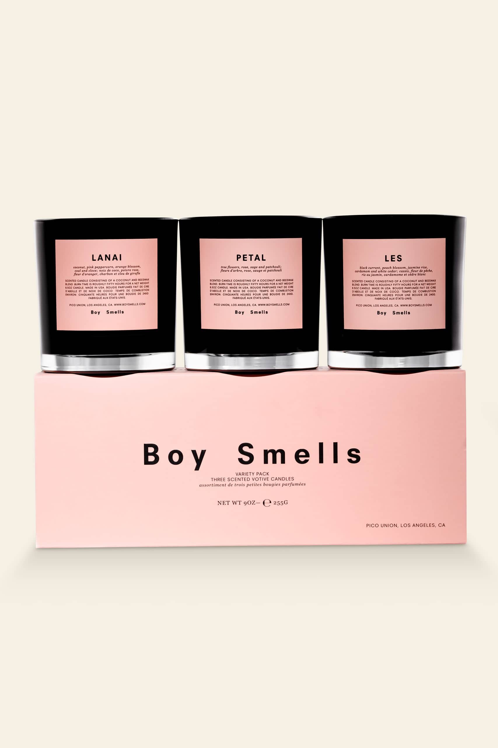 The Boy Smells Les, Petal and Lanai Votive Set features three black candles with pink labels in a sleek pink box, offering fruity and floral scents for a chic, modern ambiance.