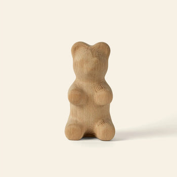 The Boyhood Gummy Bear Small by Boyhood is a smooth wooden sculpture with soft, rounded curves and no facial details, shaped like a classic candy bear and displayed against a plain, light beige background.