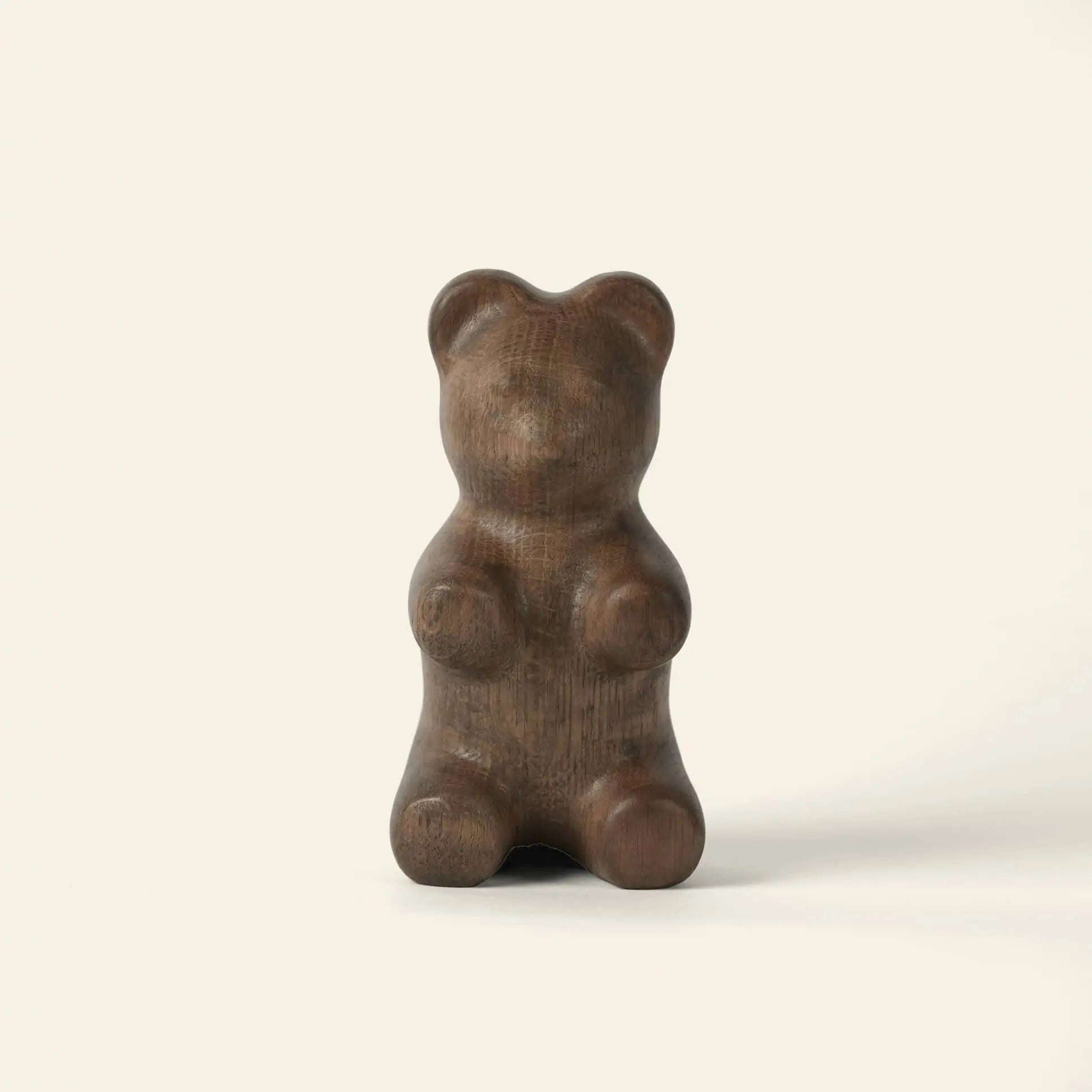 The Boyhood Gummy Bear Small by Boyhood is a smooth, dark brown sculpture shaped like a gummy bear, standing upright against a light background—an irresistible piece of eye candy.