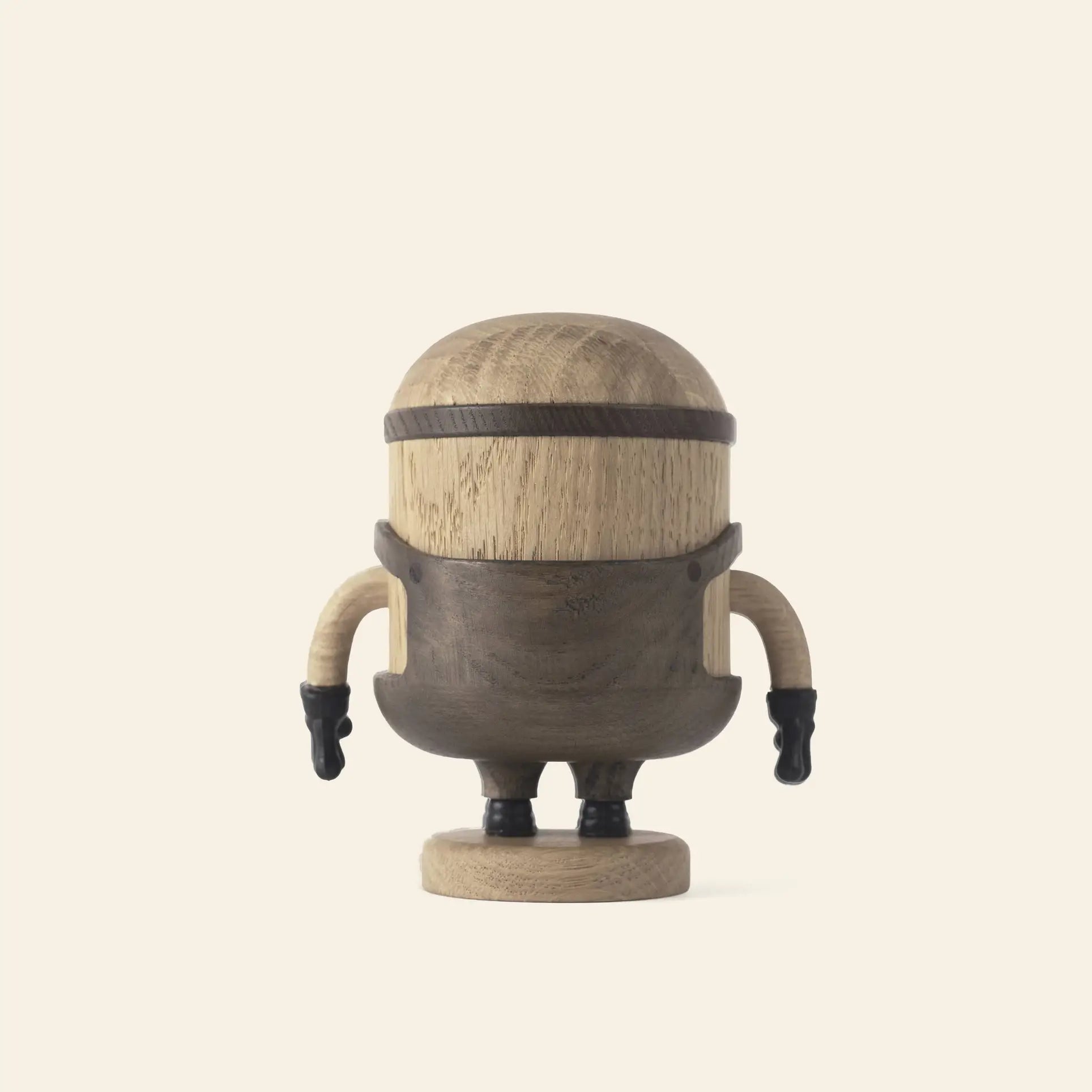 The Boyhood Minion Bob Small by Boyhood is a wooden figurine with a rounded head and body, small arms with black gloves, and a playful Minions-inspired look, standing on a circular base against a plain light background.