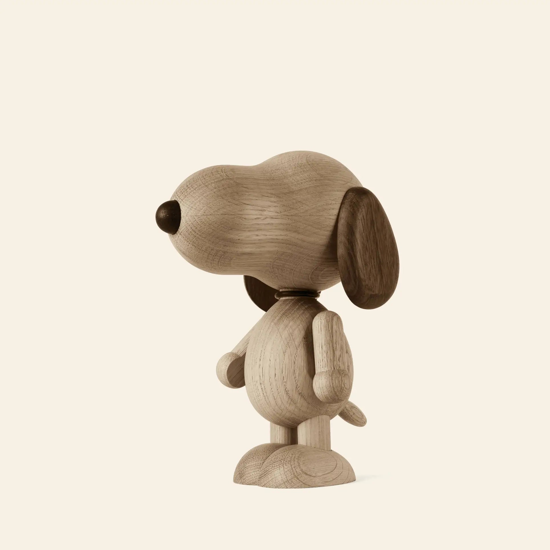 The Boyhood Snoopy Large by Boyhood is a wooden figurine of Charlie Brown’s famous cartoon dog, standing upright and facing left. It features smooth, rounded details with dark wood ears and nose against a plain beige background.