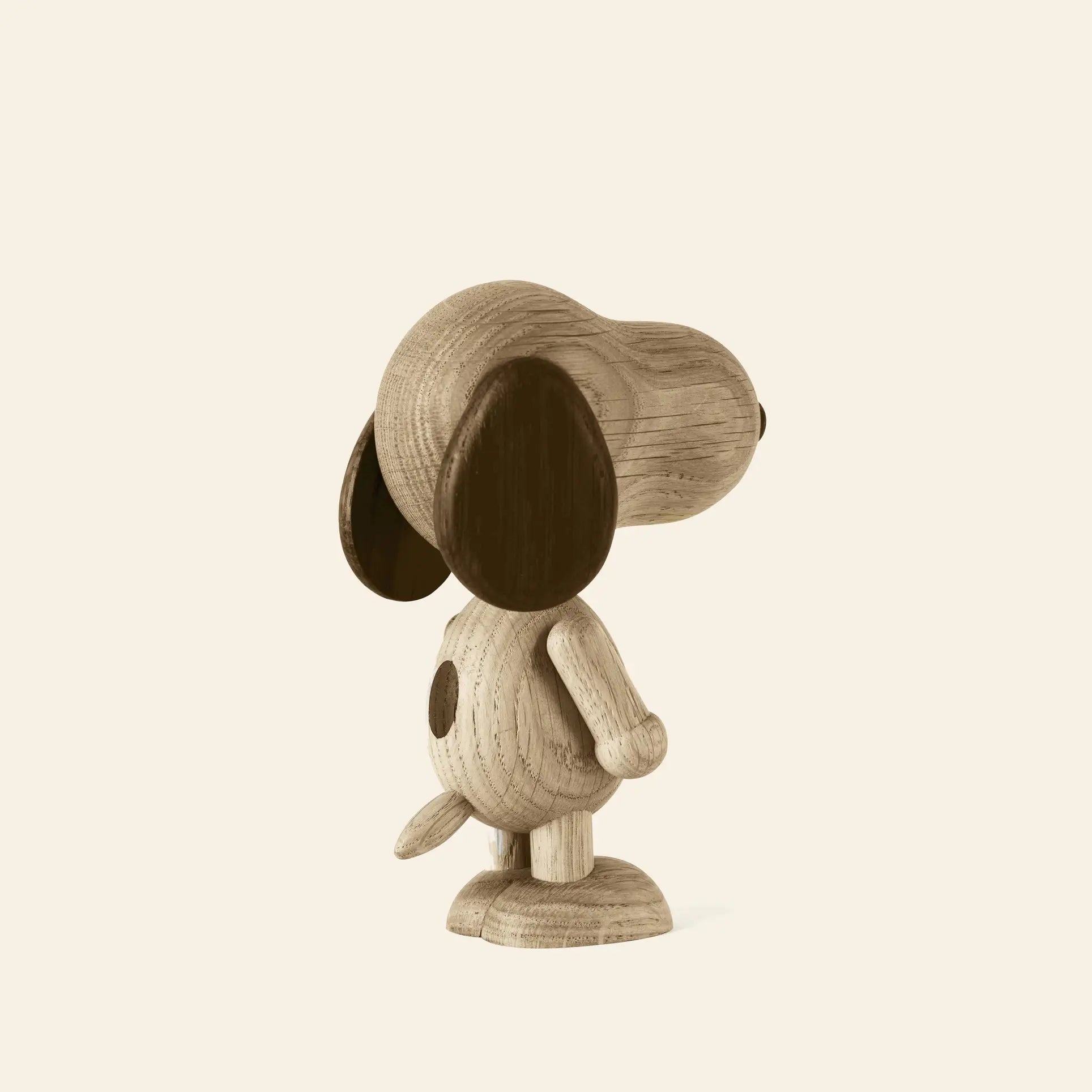 The Boyhood Snoopy Large wooden figurine by Boyhood stands upright on two legs with big dark ears and a spot on its back, inspired by Charlie Brown’s iconic dog, set against a plain light background and viewed from behind at an angle.
