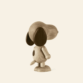 The Boyhood Snoopy Large wooden figurine by Boyhood stands upright on two legs with big dark ears and a spot on its back, inspired by Charlie Brown’s iconic dog, set against a plain light background and viewed from behind at an angle.