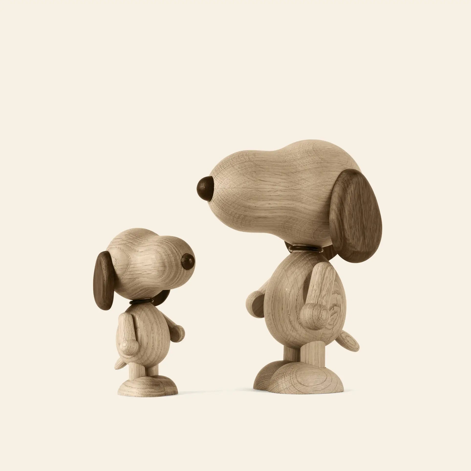 The Boyhood Snoopy Large figurine by Boyhood, crafted from smooth light and dark wood, stands alongside its smaller counterpart against a plain, light background.