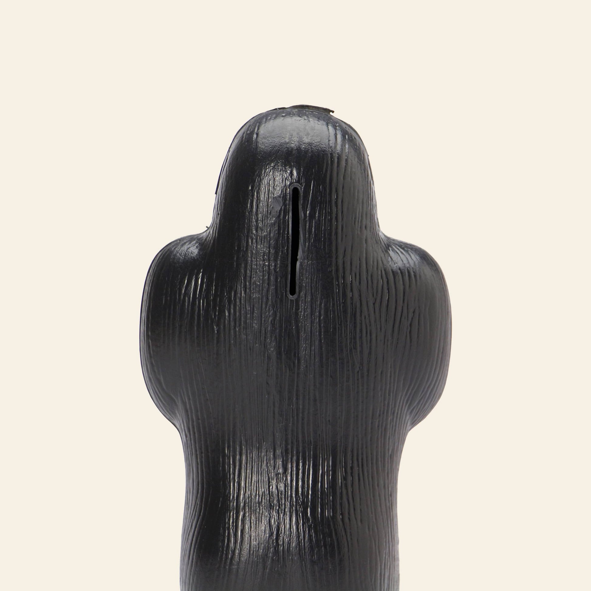 The DETAIL Gorilla Bank Small by DETAIL is a black, textured ape-shaped coin bank with a slot on top, set against a plain beige background—a unique decorative accent for any space.