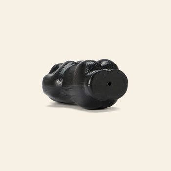 The DETAIL Gorilla Bank Small by DETAIL is a black, paw-shaped decorative piece with a hole in its base, resembling an animal or gorilla paw, and is showcased on a simple light background.