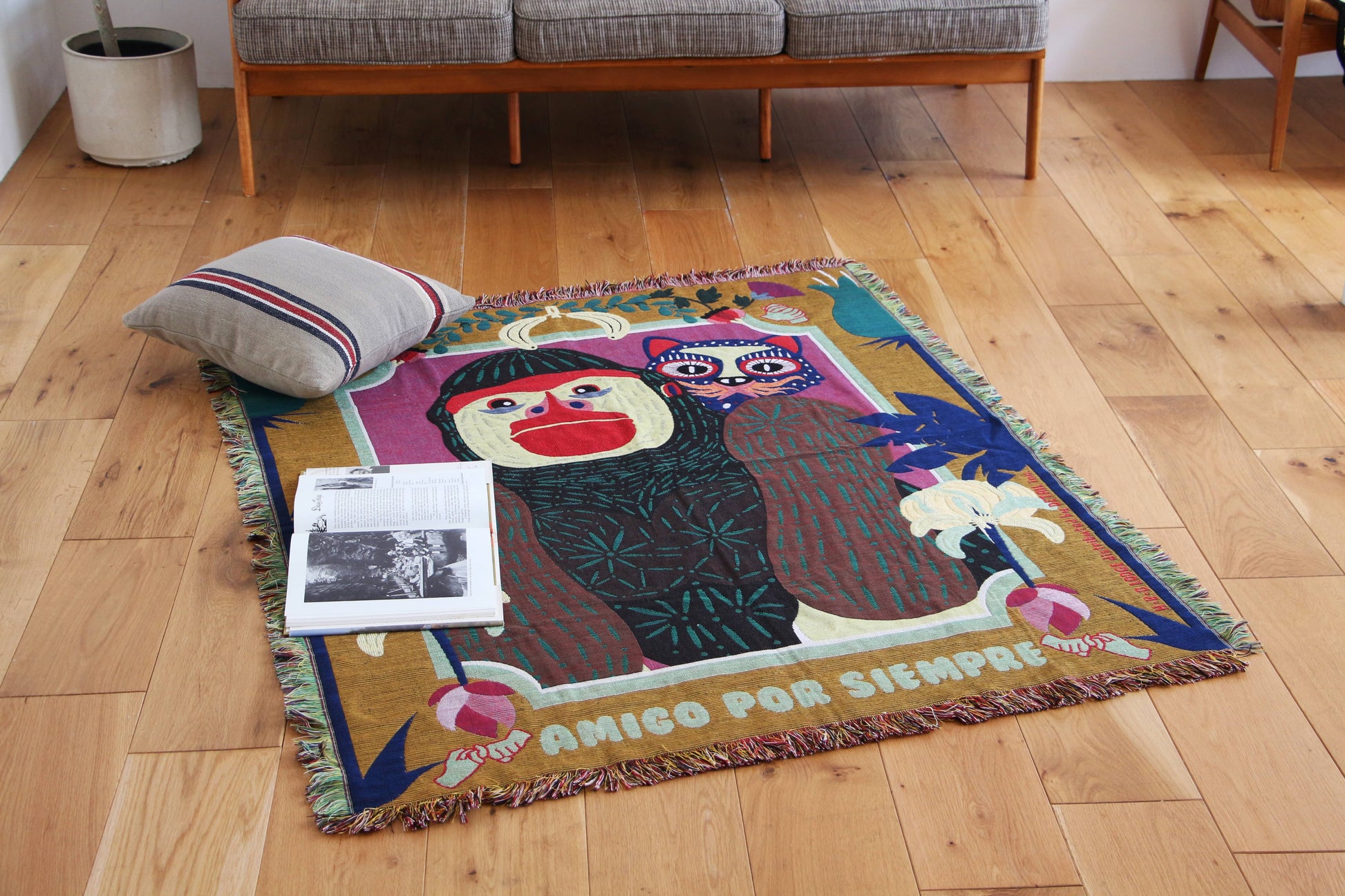 The DETAIL Gorilla Oax Throwket by DETAIL is a vibrant multicolour throw inspired by Oaxaca folk art, featuring a gorilla, pink-faced owl, leaves, and flowers with AMIGO POR SIEMPRE at the bottom.