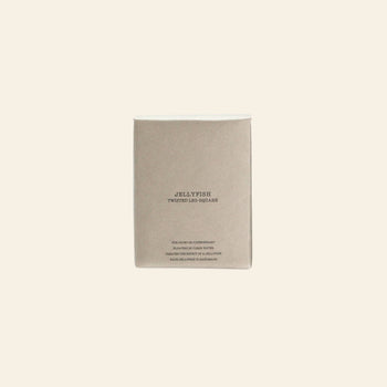 A minimalist beige box from DETAIL, labeled "DETAIL Jellyfish Twisted Leg Square," features centered text and a subtle abstract jellyfish design—ideal for modern décor fans. Displayed on a plain, light background for elegant appeal.