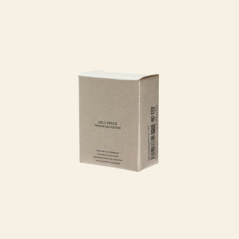 A plain, beige cardboard box labeled DETAIL Jellyfish Twisted Leg Square by DETAIL, featuring abstract jellyfish designs and a barcode on one side, stands upright against a light solid background—ideal for modern décor.