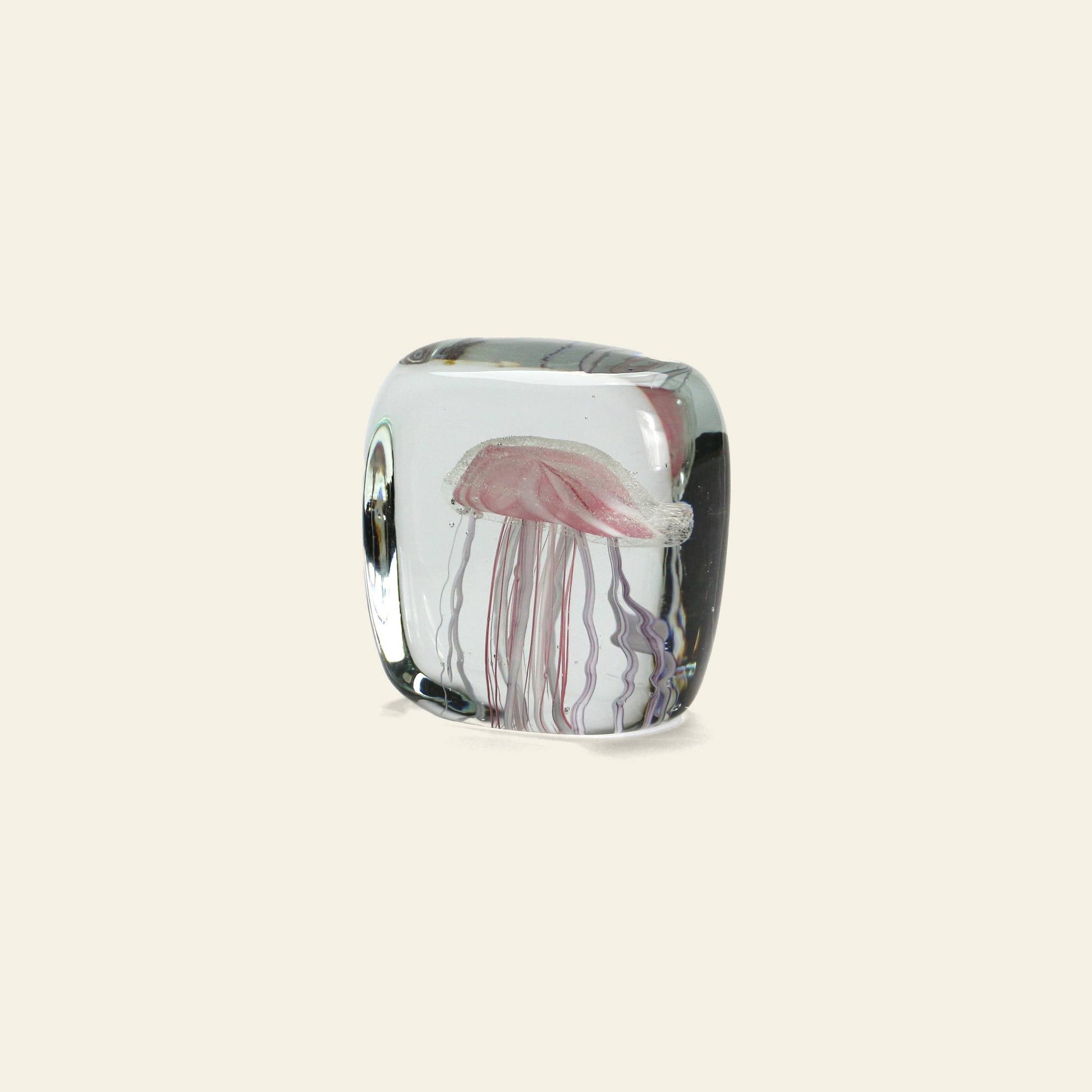 The DETAIL Jellyfish Twisted Leg Square by DETAIL features an abstract jellyfish with delicate tentacles suspended in clear glass, set against a beige background—a striking modern décor piece.