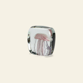 The DETAIL Jellyfish Twisted Leg Square by DETAIL features an abstract jellyfish with delicate tentacles suspended in clear glass, set against a beige background—a striking modern décor piece.
