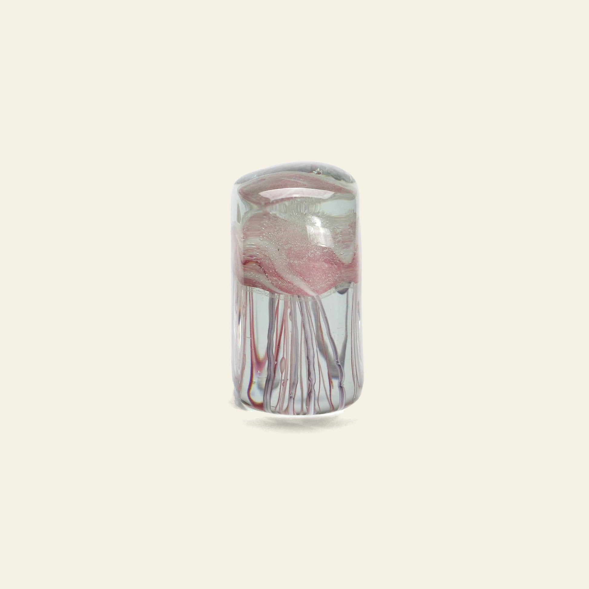 The DETAIL Jellyfish Twisted Leg Square by DETAIL features swirls of pink, white, and gray in a cylindrical glass design, standing upright on a beige background—a striking accent for modern décor.