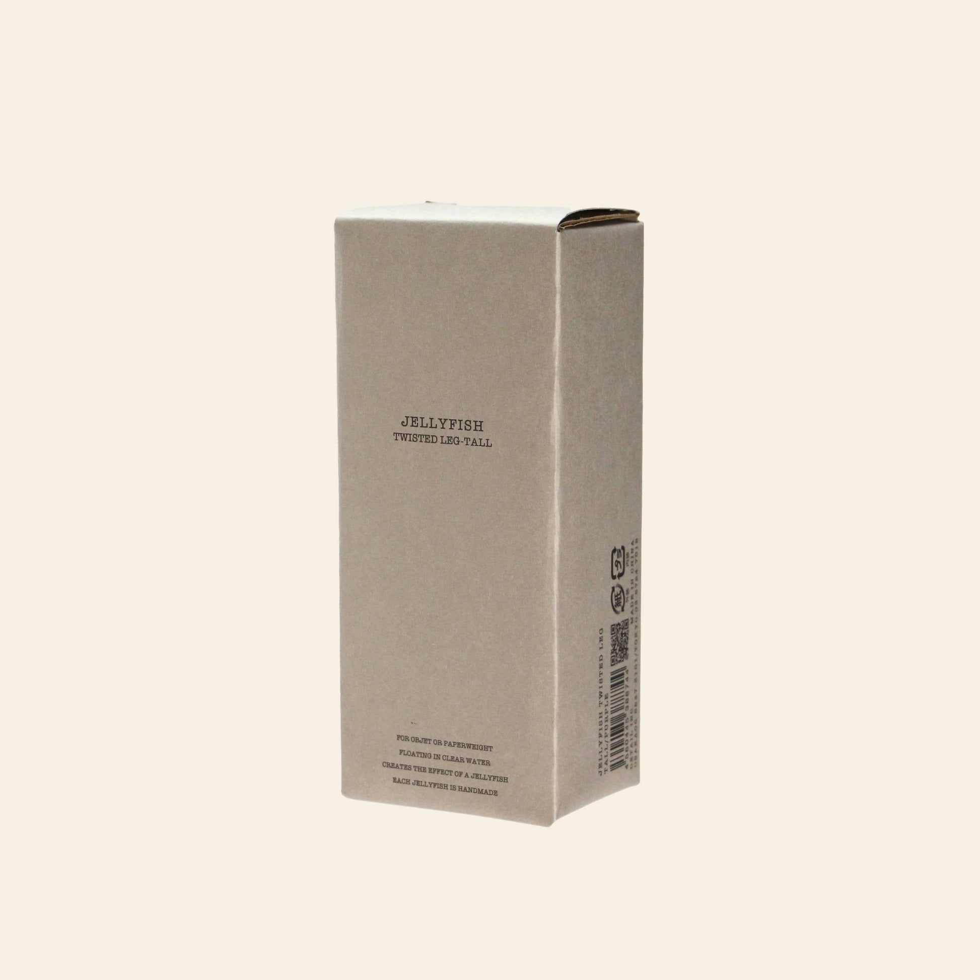 A plain, rectangular beige cardboard box with “DETAIL Jellyfish Twisted Leg Tall” printed on the front stands upright against a light background—ideal packaging for a modern art piece or tall glass décor by DETAIL.