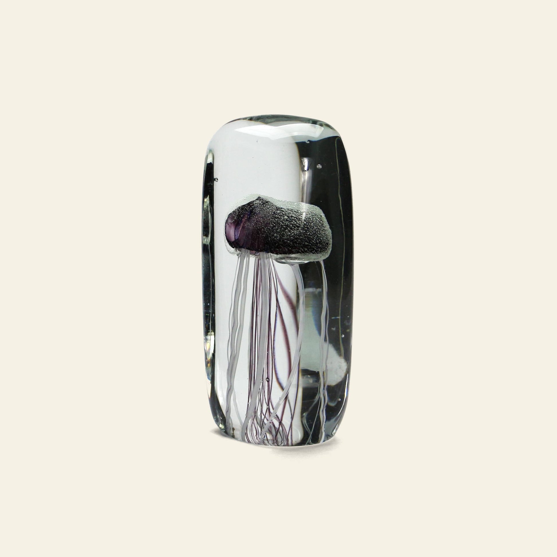 The DETAIL Jellyfish Twisted Leg Tall by DETAIL features a realistic purple jellyfish with long, thin tentacles encased in glass. Set against an off-white background, this modern art piece highlights delicate underwater beauty.