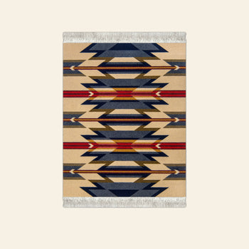 The DETAIL Mouse Rug Wyeth Trail features classic geometric motifs in beige, navy, red, and orange with fringed edges and is crafted in the iconic Wyeth Trail design by DETAIL.
