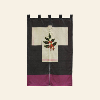The DETAIL Noren Curtain by DETAIL is a kimono-shaped textile wall hanging with a black and purple border, featuring a cream center panel adorned with plant motifs—a delicate branch of leaves and red berries inspired by classic kimono designs.