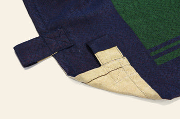 Close-up of the DETAIL Noren Curtain by DETAIL, highlighting its dark blue fabric, green-beige underside, reinforced stitched loop for hanging, and subtle kimono-inspired patterns.
