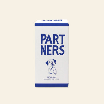 A rectangular box labeled DETAIL Partners Nesting Dolls features "PARTNERS" in large blue letters and a Dalmatian illustration below, with blue borders, a light background, and a charming dog design reminiscent of hand-painted wood.